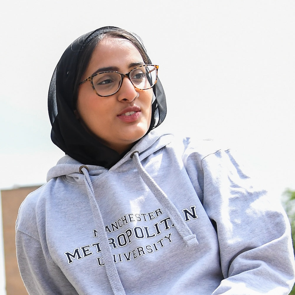 Student with glasses and dark hair wearing grey MMU branded hoodie